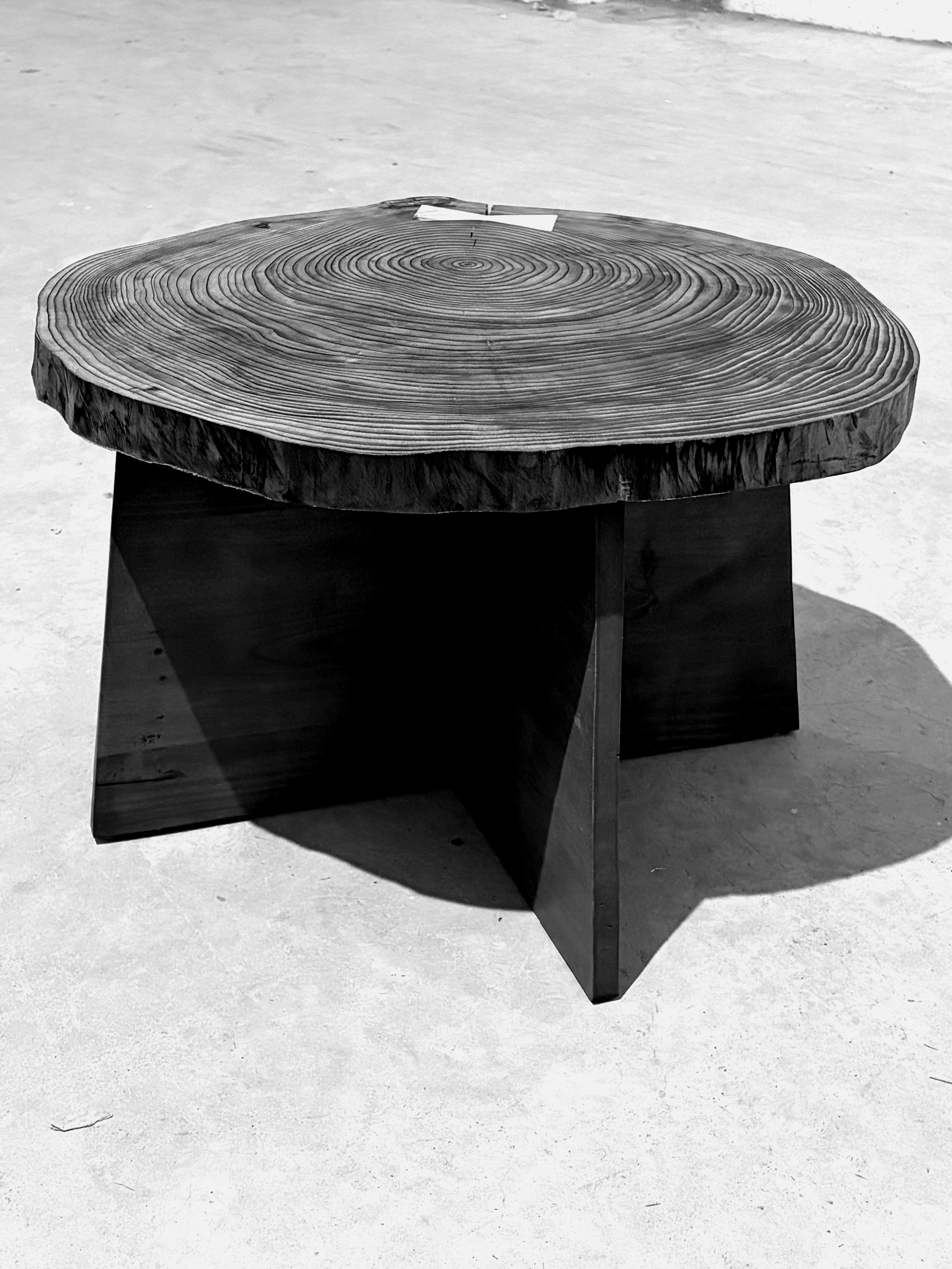 Round live-edge cedar dining table on a cruciform base